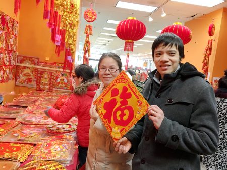 美国华人夫妇陈先生和太太逛年货市场,买对联和福字。 (于佩/大纪元)