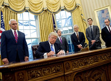 TOPSHOT - US President Donald Trump signs an executive order in the Oval Office of the White House in Washington, DC, January 23, 2017. Trump on Monday signed three orders on withdrawing the US from the Trans-Pacific Partnership trade deal, freezing the hiring of federal workers and hitting foreign NGOs that help with abortion. / AFP / SAUL LOEB (Photo credit should read SAUL LOEB/AFP/Getty Images)