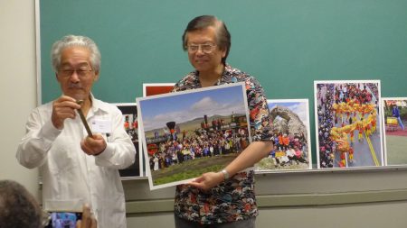 紐約華裔攝影師李揚國與多倫多客家會議發起人羅金生(Keith Lowe,左)在會上,李揚國介紹他與一些華人,在橫跨鐵路建成145周年之際,號召了200名華人和其他亞裔,在複製的火車機車前面合影,彌補當年鐵路完工慶祝活動照片看不到華工身影的缺憾,他們還步行到數英里外的中國拱門。