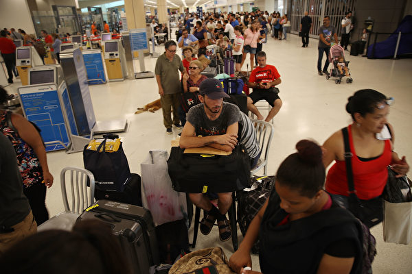 旅客在聖胡安市內的機場大排長龍，等待一位難求的機位。(Joe Raedle/Getty Images)