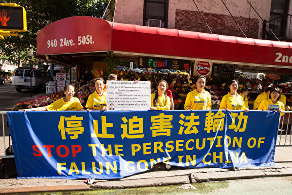 纽约法轮功学员张玉华21日在联合国门前举牌呼吁营救他两天前刚被抓走的丈夫、南京法轮功学员马振宇。（戴兵/大纪元）