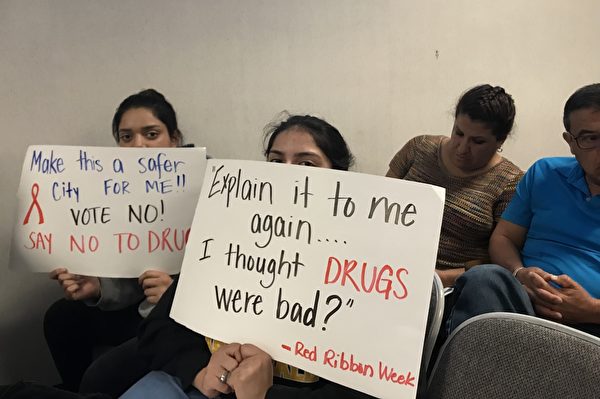 學生舉標語抗議，上寫：請再給我解釋一遍……我以為毒品是不好的。（劉菲／大紀元）