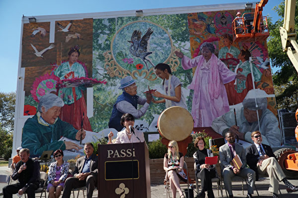 10月4日，賓州亞裔老人服務中心PASSi創辦人及總裁崔英佳女士（Im Ja Choi） 在壁畫揭幕剪綵前演講。右上方藝術家Ann Northrup正在裝上最後一片壁畫。（肖捷/大紀元）