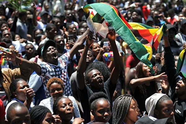 TOPSHOT - A man holding a flag of Zimbabwe takes part in a demonstration of University of Zimbabwe's students, on November 20, 2017 in Harare, to demand the withdrawal of Grace Mugabe's doctorate and refused to sit their exams as pressure builds on Zimbabwe's President Robert Mugabe to resign.<br /> Zimbabwe's President faced the threat of impeachment by his own party on November 20, 2017, after his shock insistence he still holds power in Zimbabwe despite a military takeover and a noon deadline to end his 37-year autocratic rule.<br /> / AFP PHOTO / - (Photo credit should read -/AFP/Getty Images)