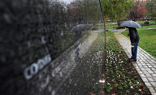 圖為2009年11月10日，在保加利亞首都索非亞，一名男子在寫有兩萬名共產黨統治時期受難者的紀念碑前尋找親人的名字。共產黨曾統治保加利亞45年，今天已不復存在。(DIMITAR DILKOFF/AFP/Getty Images)