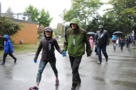 在當天的本拿比市的泰瑞福克斯長跑中，有一對老年夫婦，手牽手地在雨中長跑。（童宇/大紀元）
