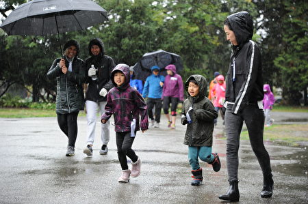 在當天的本拿比市的泰瑞福克斯長跑中，有家長帶著小孩，堅持在雨中長跑。（童宇/大紀元）