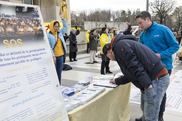 过往民众和游客签署请愿书，呼吁国际社会制止中共对法轮功学员的迫害。（关宇宁/大纪元）