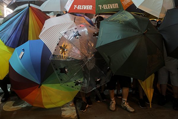 Protesters carry umbrellas to protect themselves as they face the police in the Mong Kok district in Kowloon after taking part in a march to the West Kowloon rail terminus against the proposed extradition bill in Hong Kong on July 7, 2019. - Tens of thousands of anti-government protesters rallied outside a controversial train station linking the territory to the Chinese mainland on July 7, the latest mass show of anger as activists try to keep pressure on the city's pro-Beijing leaders. (Photo by VIVEK PRAKASH / AFP)