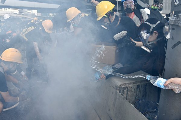 警方在金鐘夏慤道一再施放催淚彈。示威者用水澆滅催淚彈。（ANTHONY WALLACE/AFP/Getty Images)