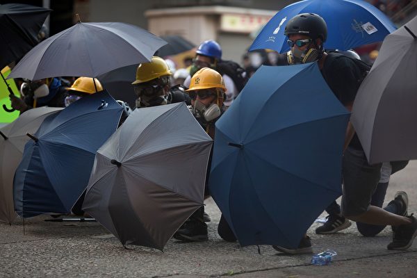 黃大仙處警方持續施放多枚催淚彈。示威者用雨傘遮擋。（ISAAC LAWRENCE/AFP/Getty Images)