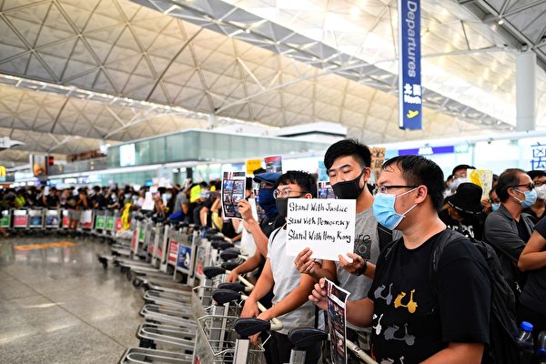 8月13日，大批港人继续在机场抗议港警8.11施暴，手举标语。