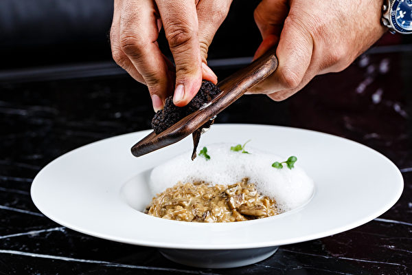 risotto with truffles served in the white plate on the black background（Fotolia）