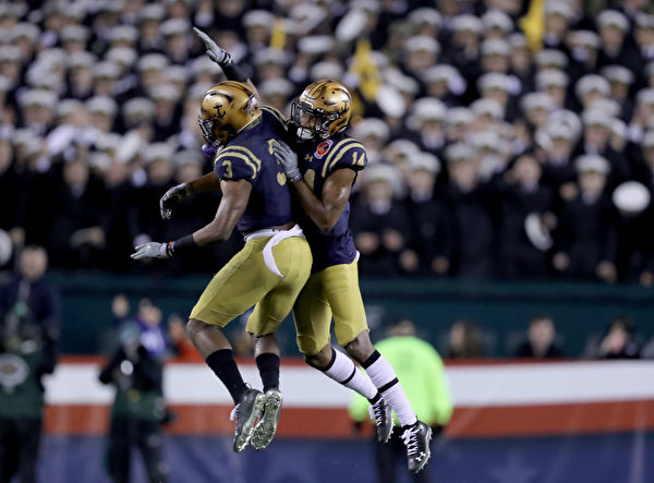 PHILADELPHIA, PENNSYLVANIA - DECEMBER 14: Micah Farrar #14 and Cameron Kinley #3 of the Navy Midshipmen celebrates after Navy Midshipmen recovered the ball in the fourth quarter against the Army Black Knights at Lincoln Financial Field on December 14, 2019 in Philadelphia, Pennsylvania.The Navy Midshipmen defeated the Army Black Knights 31-7. (Photo by Elsa/Getty Images)