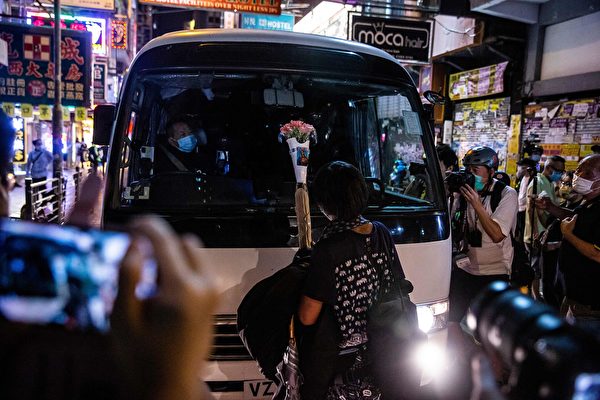 5月10日，香港市民在商場等地抗議。一位女士拿著一束母親節鮮花站在防暴警察車子前面。（ ISAAC LAWRENCE/AFP via Getty Images）