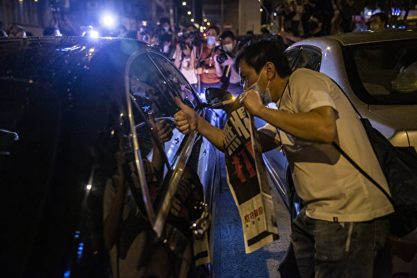 8月12日凌晨，港人在旺角警署举着《苹果日报》表示抗议，图为港人向刚获释、已坐在车中的黎智英竖起大拇指，表示支持。（ISAAC LAWRENCE/AFP via Getty Images）