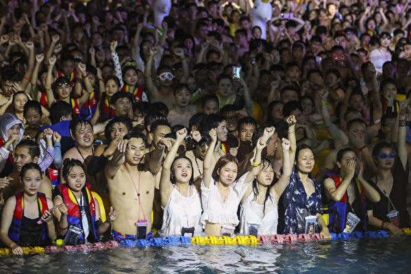 武汉“玛雅海滩”水上乐园日前举办泳池电音派对，水池里全部挤满了人。(STR / AFP) 