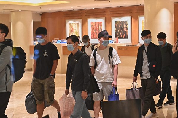 香港五星级酒店帝苑酒店（The Royal Garden）因有员工染疫，近100名职员要接受检疫隔离。图为酒店员工走出酒店后被送往隔离地点。（宋碧龙/大纪元）