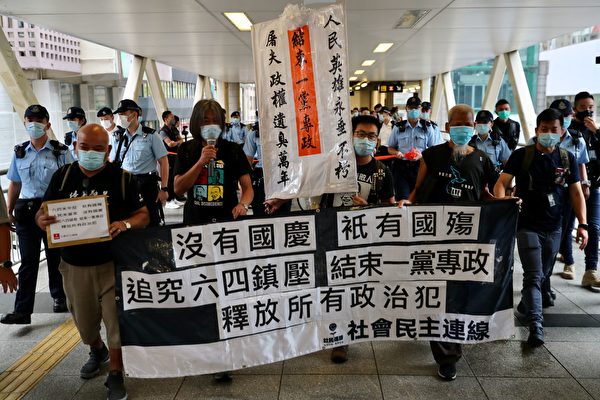 10月1日，香港支联会及社民连等团体到中联办外抗议，并要求释放12名港人。警察紧跟其后。（MAY JAMES/AFP via Getty Images)）