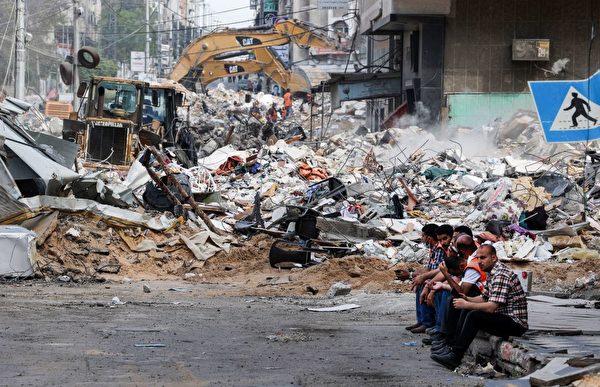 5月16日，以色列對哈馬斯控制的加沙空襲後，挖掘機正在清理被毀的建築物廢墟。（Mahmud Hams/AFP via Getty Images）