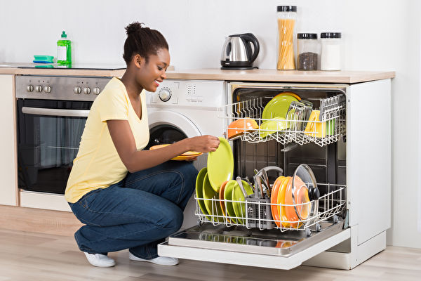 Happy,Young,Woman,Arranging,Plates,In,Dishwasher,At,Home