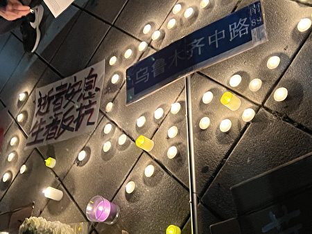 2022年11月29日中國留學生在紐約中領館前集會，地上擺著蠟燭悼念新疆大火的死難者。
