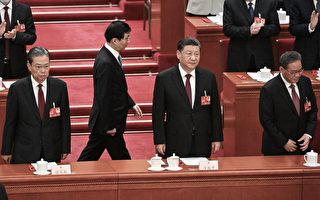 2023年3月10日，中共两会上，习近平（右二）、李强（右一）、赵乐际（左一）站在主席台上，王沪宁（左二，后排）从后面经过。（NOEL CELIS/AFP via Getty Images）