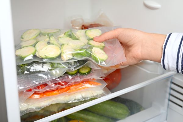 Woman Putting Vacuum Bags With Vegetables Into Fridge Closeup Food