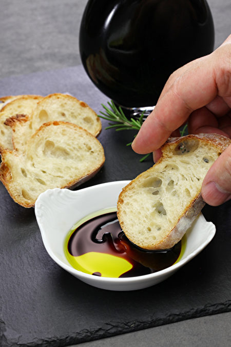 Dipping Baguette Into Balsamic Vinegar And Olive Oil Sauce