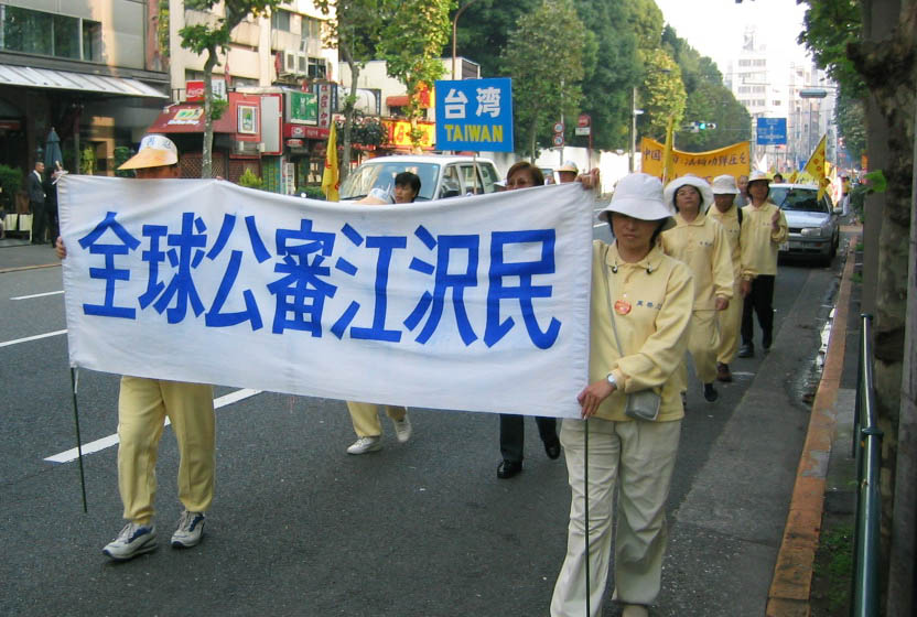 打着“全球公审江泽民”的横幅行进的队伍(大纪元)