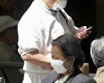圖為一名面戴口罩的婦女在北京一所醫院裏讀報。(法新社)