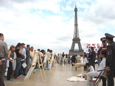 2004年7月18日，在巴黎埃菲爾鐵塔對面的人權廣場，真人模擬和展板展示江澤民迫害中國大陸法輪功學員所用的部份酷刑 。(大紀元) <br /></a><figcaption id=