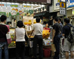 炎热天气为街头小食店带来更多顾客，市民和游客停下脚步购买饮料如果汁等解渴。(大纪元)