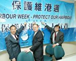 梁家傑、徐嘉慎、甘乃威（由左至右）在記者會上將藍絲帶貼在保護維港周的橫額上，以表達保護維港的心意。（大紀元記者吳璉宥攝）