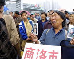 2005年8月18日，一位农妇拿着被当地官员害死的儿子照片，在陕西西安新设的一个访民接待処排队等待上交申述材料。新的上访条例为减少去北京上访的访民人数，规定访民必须先在当地登记注册。(STR/AFP/Getty Images)