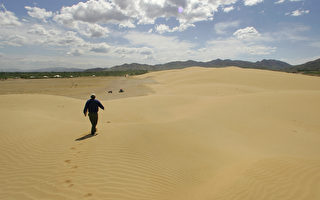 中国沙尘暴问题日益严重，很多地方都已被黄沙淹没。图为一名男子在北京以北90公里処的天漠沙漠上行走。（FREDERIC J. BROWN/AFP/Getty Images）