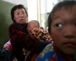 安徽省阜阳市EV71肠病毒疫情持续扩大，目前已知最少有1,520名儿童受到感染，其中20人不治死亡。图为一名妇人抱着染上EV71的孩子，在当地一家医院就医。（ChinaPhotos/GettyImages）