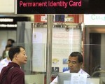 圖為一名香港市民由大陸返港,正在香港人境處櫃位接受職員審核身份。(AFP)