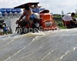 台风袭击了菲律宾海东北海岸的吕宋岛，图为蒙特尔居民骑三轮车穿过被淹没的街道。（法新社）