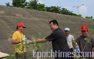檢察長賴哲雄遞上礦泉水慰勉社會勞動人清理環境的辛勞。(攝影：許享富/大紀元)