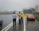 胡錦濤的車隊開始經過吉隆坡國際機場的收費站之時，法輪功學員冒雨向著收費站舉起兩幅橫幅：「法輪大法好」和「立即停止迫害」。（攝影：馬庭國/大紀元）