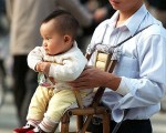 在中共「一胎化」的政策之下，中國大陸的性別比例失衡，男性遠多於女性。圖為一位父親帶著孩子。（AFP）
