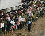 舟曲大批領取救援物資的災民在泥濘道路上艱難前行。（法新社）