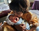 8月25日，巴基斯坦水患最严重的瑙谢拉，一个小女孩抱着刚出生不久的婴儿。（AFP）
