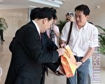 法輪功學員（右）伺機送上控訴陝西代省長趙正永訴狀的禮物袋給陝西省副省長景俊海（左）。（攝影：施予 ／大紀元）