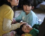 图为2011年3月11日，仙台，一名母亲带着儿女到避难所避难。(AFP PHOTO / Philippe Lopez)