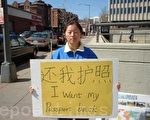 石偉胸前掛著寫有「還我護照」字樣的黃色牌子，在中國大使館簽證處的街對面豎起有關法輪功被迫害的宣傳畫，並向路人散發有關法輪功學員被迫害情況的資料。 （大紀元）