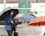 4月7日，“幅射雨”的传闻加重了民众的恐慌，行色匆匆的人流中，撑雨伞、戴口罩者随处可见。图为韩国首尔市区道路上的行人。（摄影：全宇/大纪元）