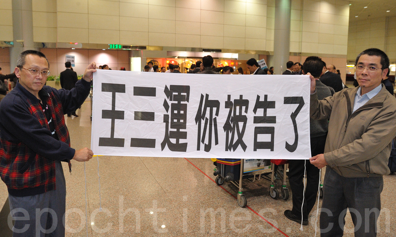 你被告了-中共人權惡棍安徽省長王三運2011年來台灣,法輪功學員在機場中拉橫幅表達訴求。(宋碧龍/大紀元)