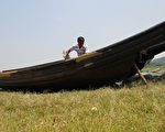 5月27日，水位则持续历史同期最低。图为当地渔民冯家棋正在草地上维护自己的渔船。（大纪元资料室）